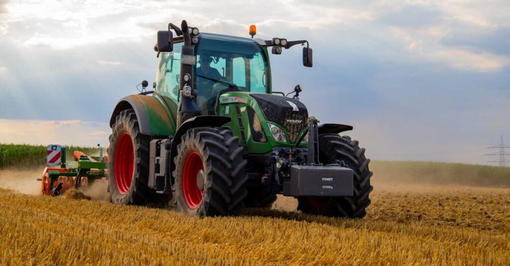 A powerful green tractor plowing a dusty wheat field under a cloudy summer sky in rural Germany.